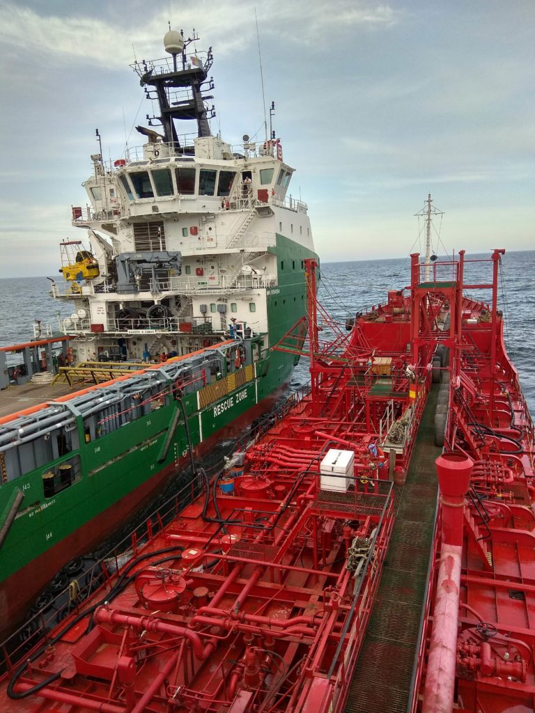 Bunker vessel alongside a red-hulled ship, fenders between the two hulls in open water.
